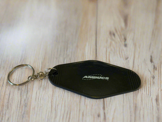 Black keychain with 'AMBUCS' logo on a document