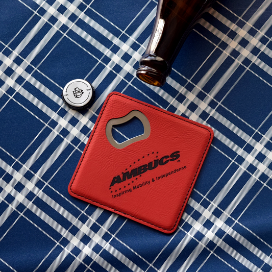 Square red leather covered bottle opener. The AMBUCS logo is printed in black with the words inspiring mobility and independence in black letters. 